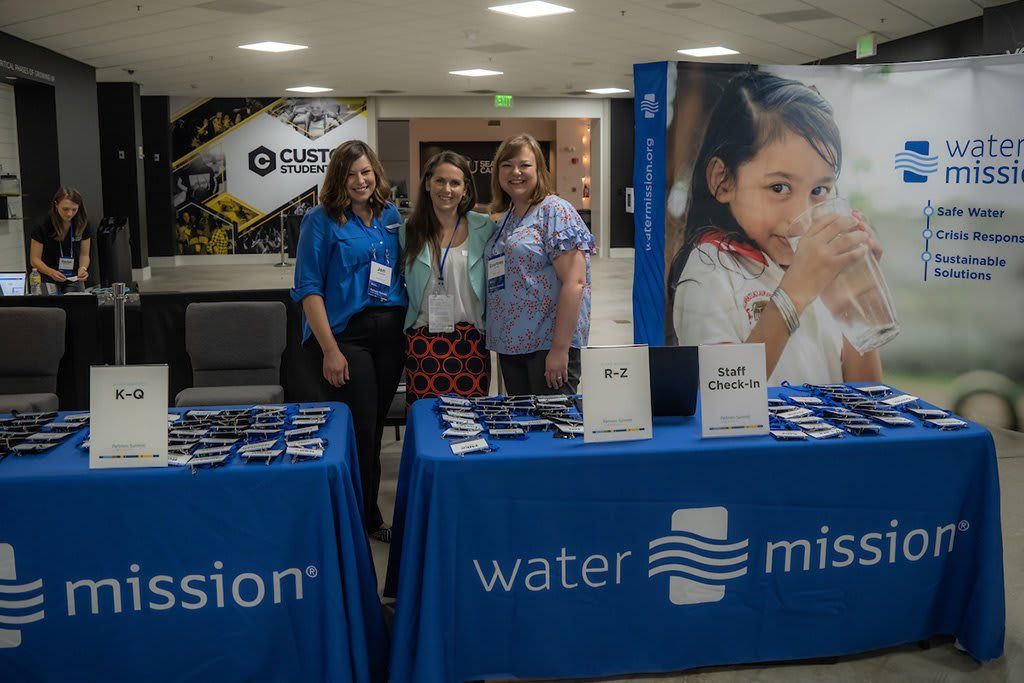 Women at Water Mission tables of merch