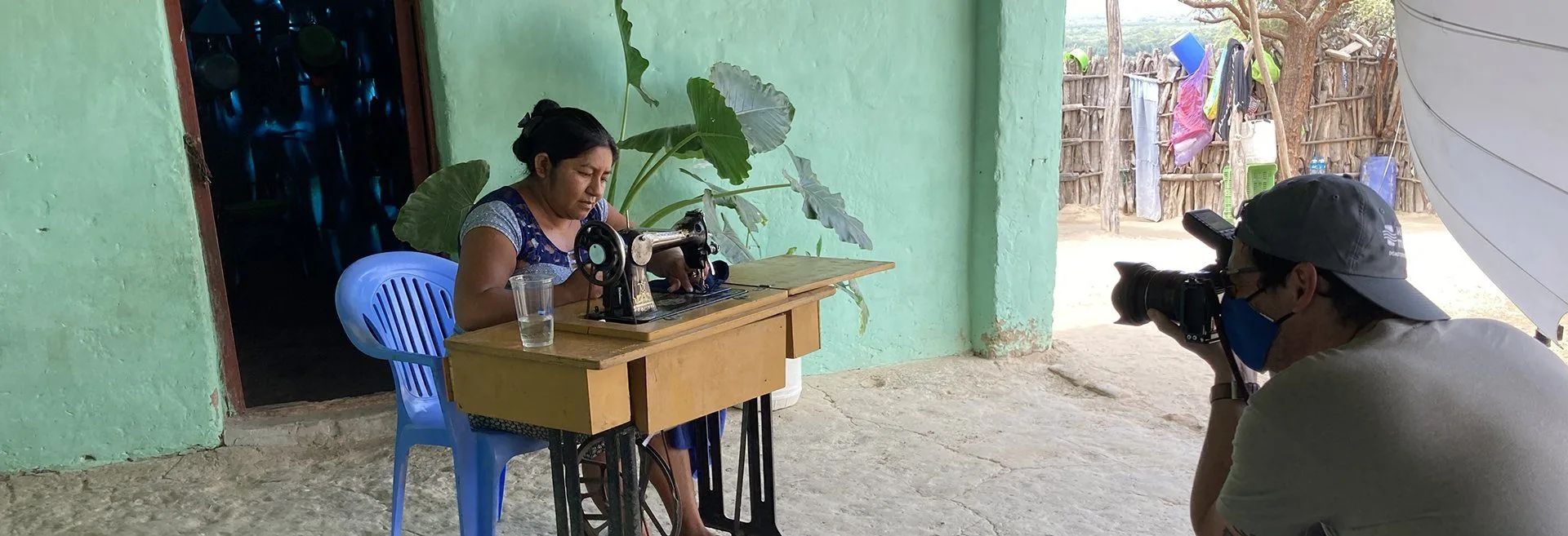 Photographer taking photo of woman sewing