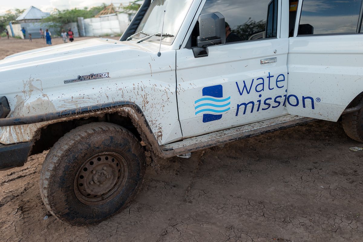 Water Mission logo on muddy white Land Cruiser door